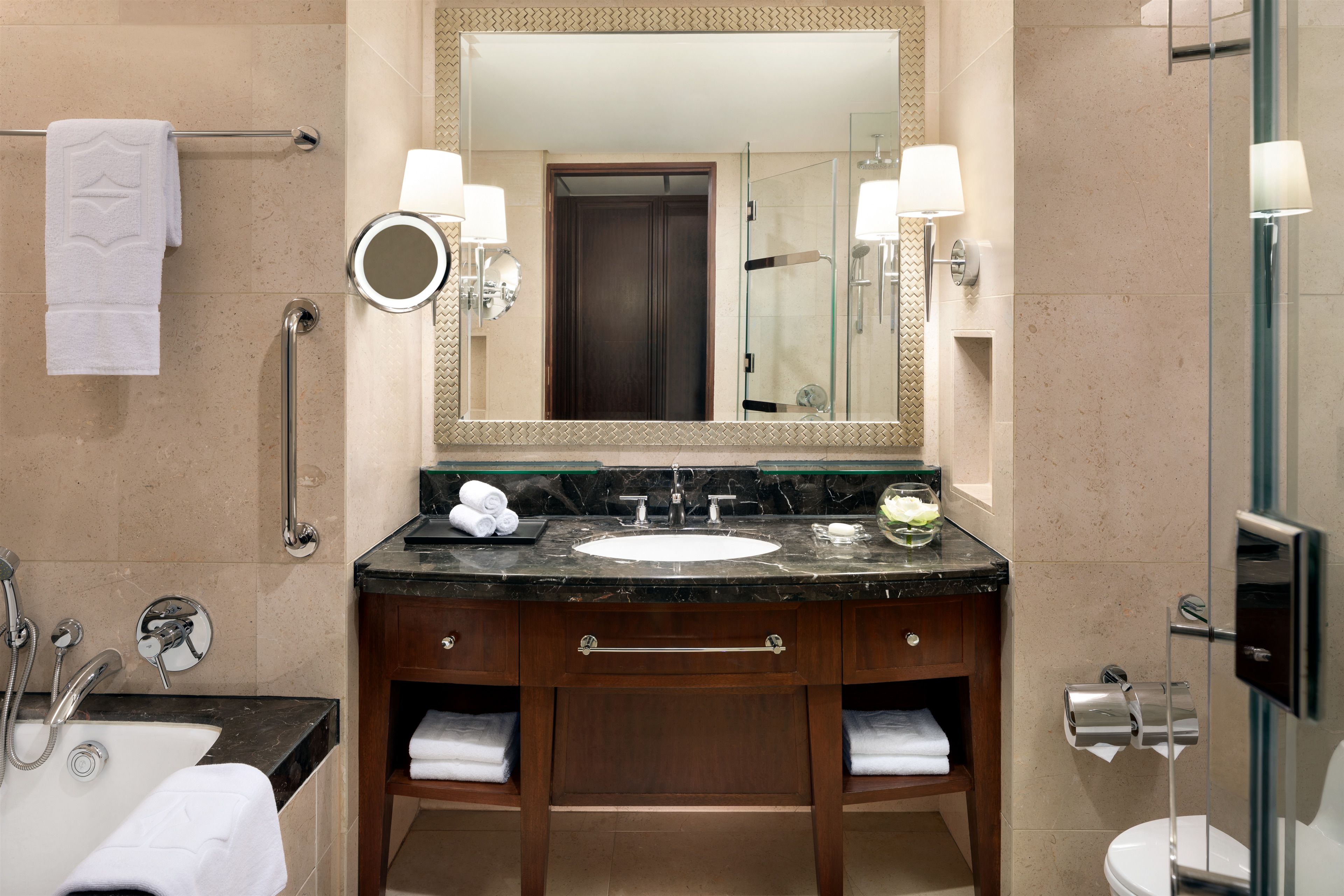 A bathroom with a sink, mirror, towel rack, and a glass shower enclosure.