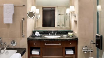 A bathroom with a sink, mirror, towel rack, and a glass shower enclosure.