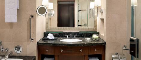 A bathroom with a sink, mirror, towel rack, and a glass shower enclosure.