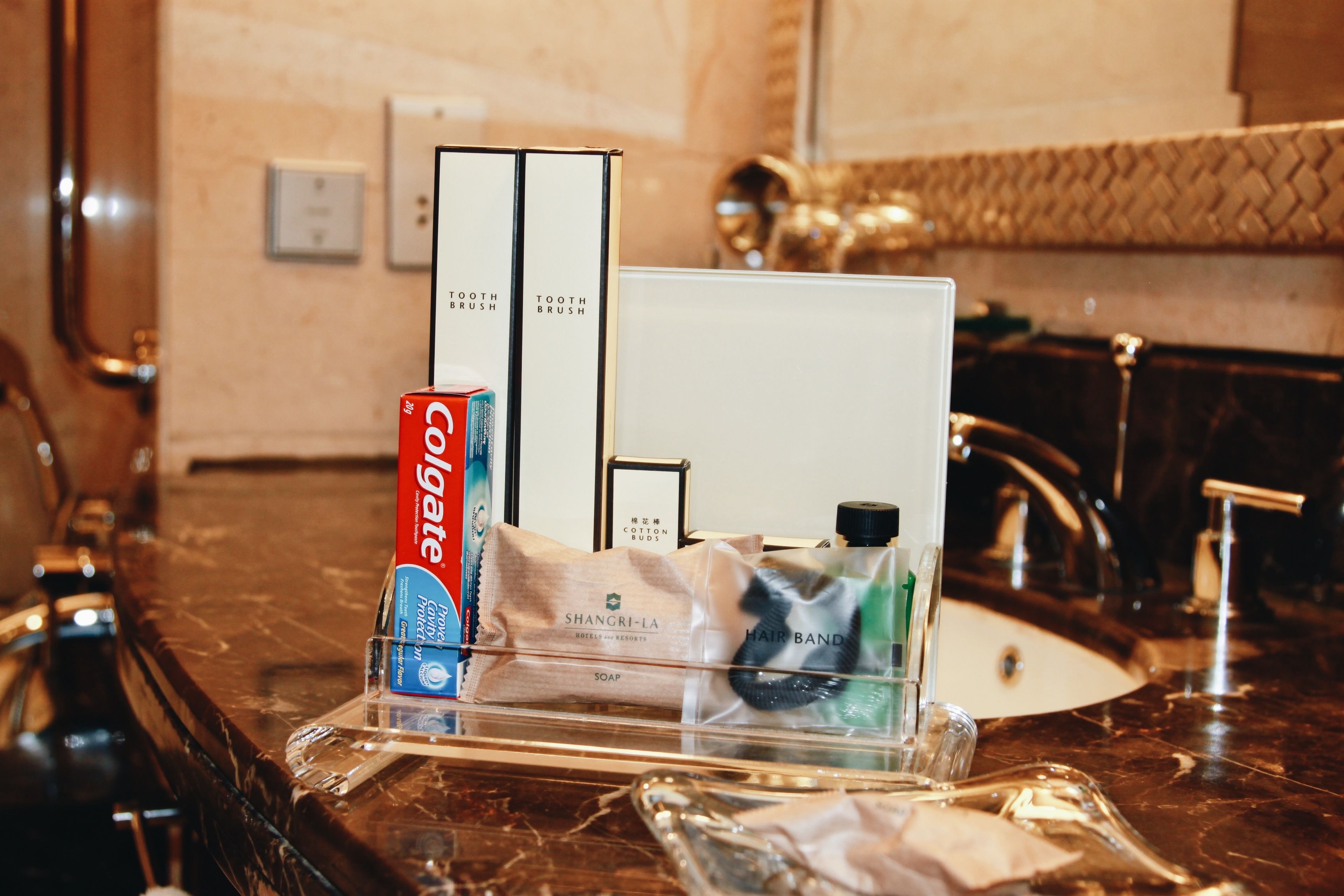 A bathroom counter with a toothbrush, toothpaste, and a hairband.