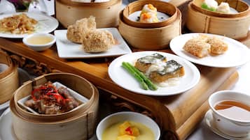 Variedad de platos asiáticos, como dim sum y un tazón de sopa con fruta.
