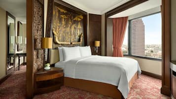 A hotel room with a large bed, two bedside tables with lamps, a large mirror, and a view of a cityscape through a large window.