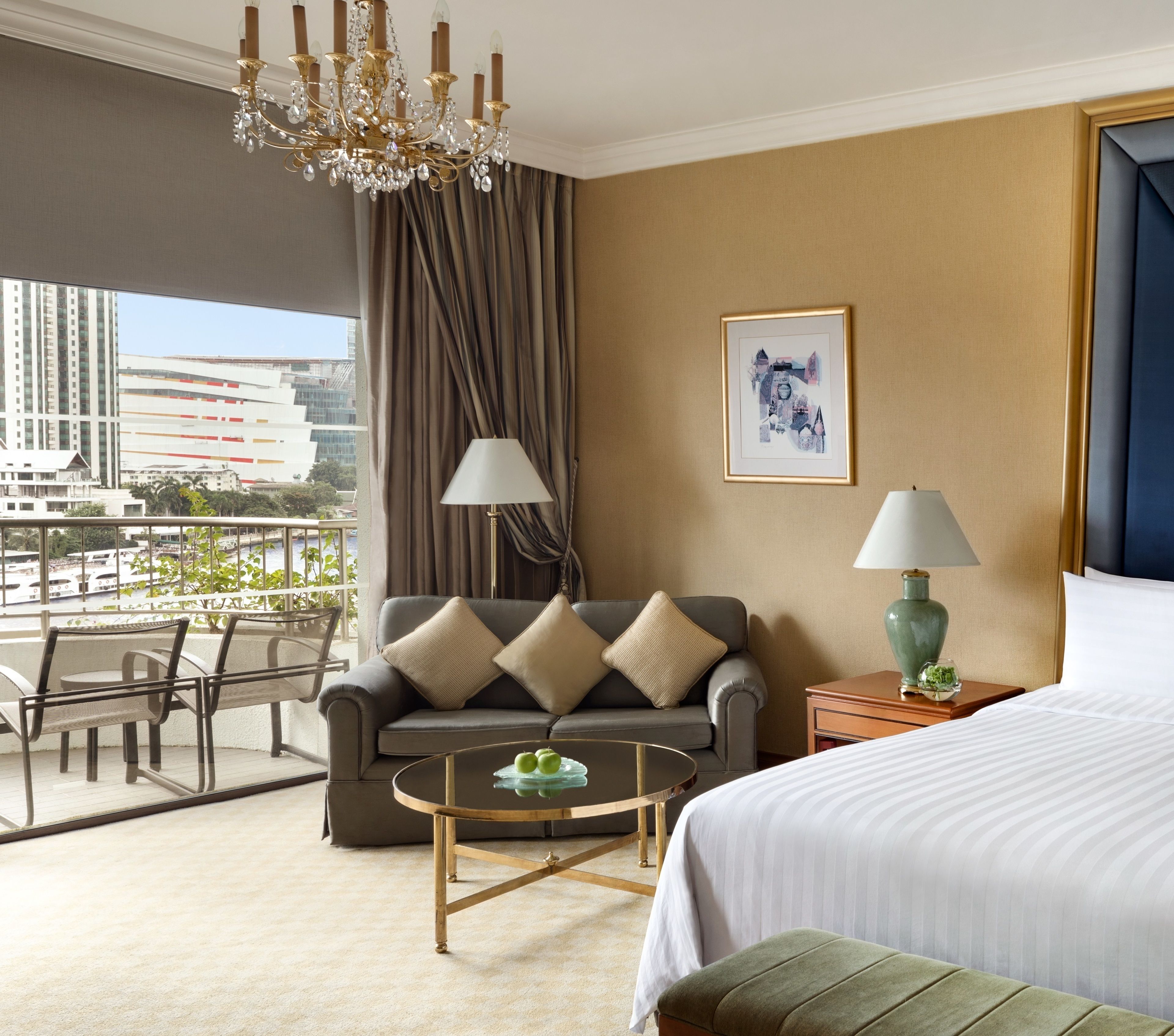 A hotel room with a large bed, a sofa, a coffee table, and a view of the cityscape.