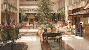 A spacious atrium with high ceilings, large windows, and a central fountain.