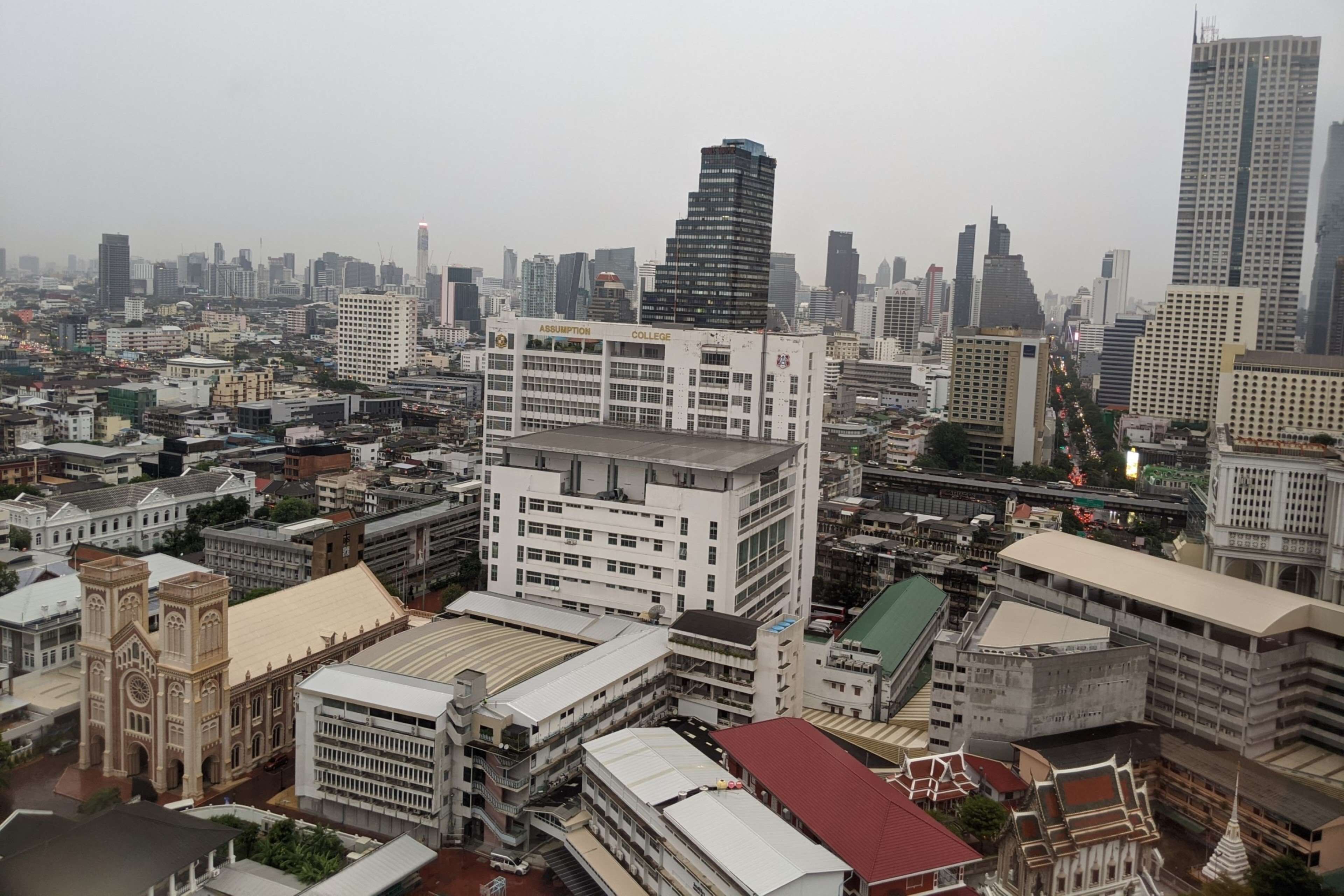 A cityscape with a prominent Assumption College building, surrounded by various other buildings and a busy street.
