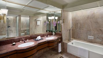 A luxurious bathroom with two sinks, a large mirror, a bathtub, and a marble floor.