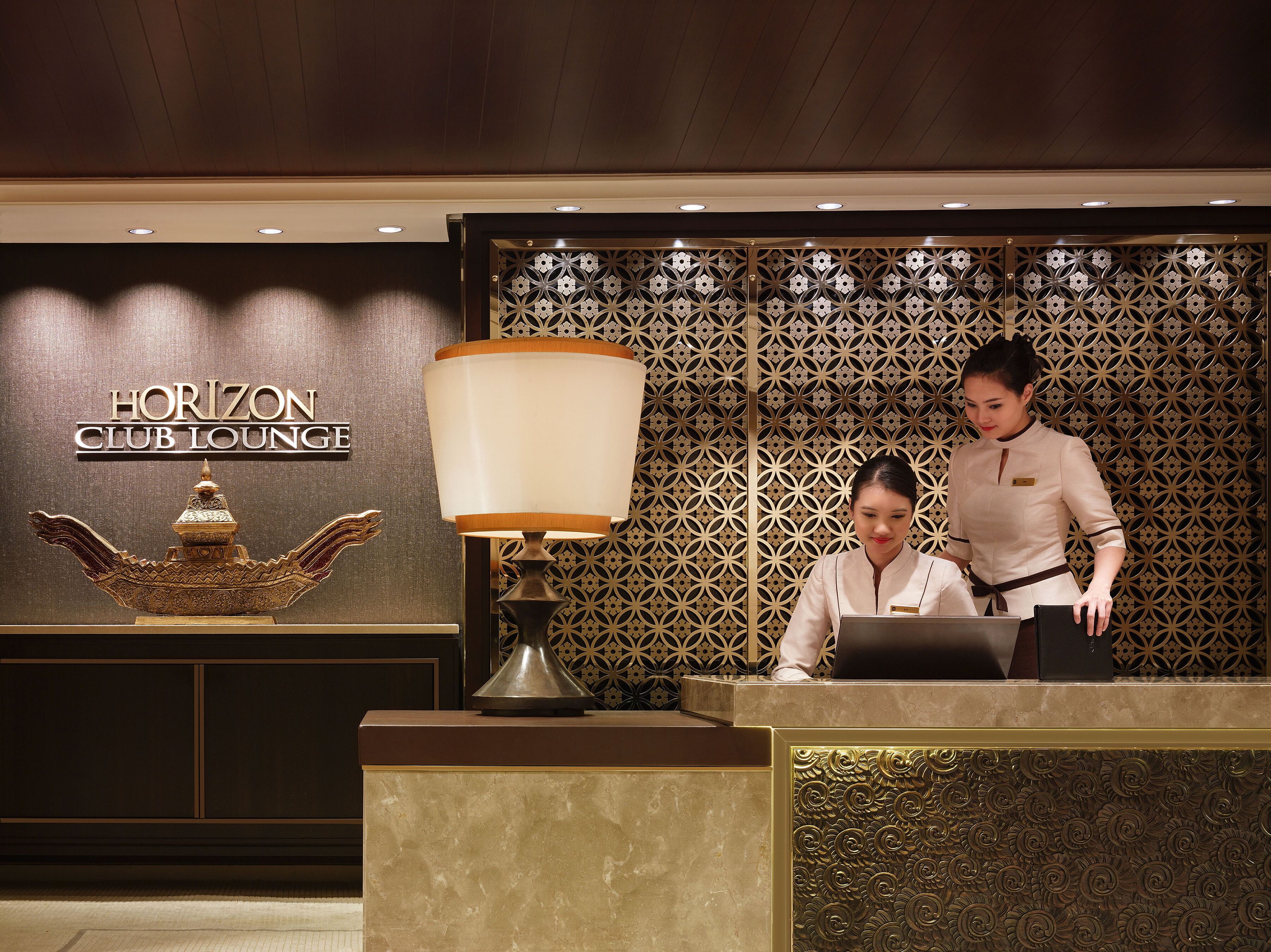 A reception desk with a sign reading "Horizon Club Lounge" and a decorative lamp.
