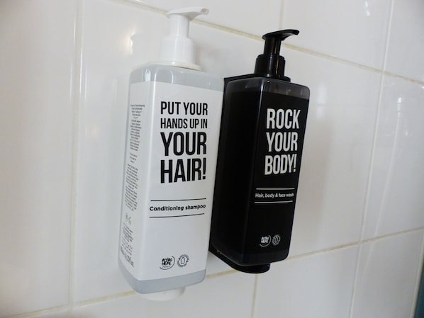 Two bottles of shampoo on a tiled wall. - Ibis Paris Meudon Velizy (Meudon)