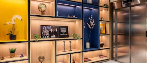 A modern interior with a wooden panel wall, a digital clock, and a stainless steel elevator.