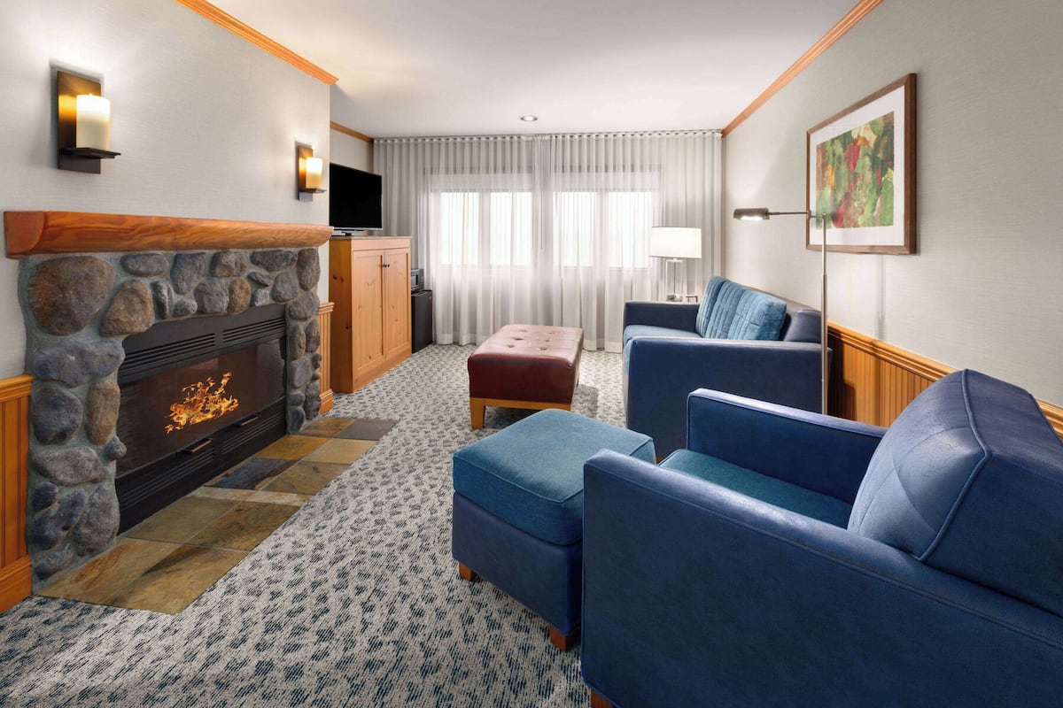 A living room with a stone fireplace, blue upholstered sofas, a television, and a lamp.