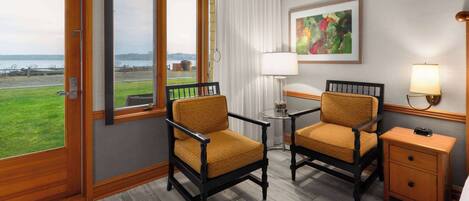 Habitación de hotel con dos sillones, una mesita, una mesita de noche, una lámpara y un cuadro en la pared.