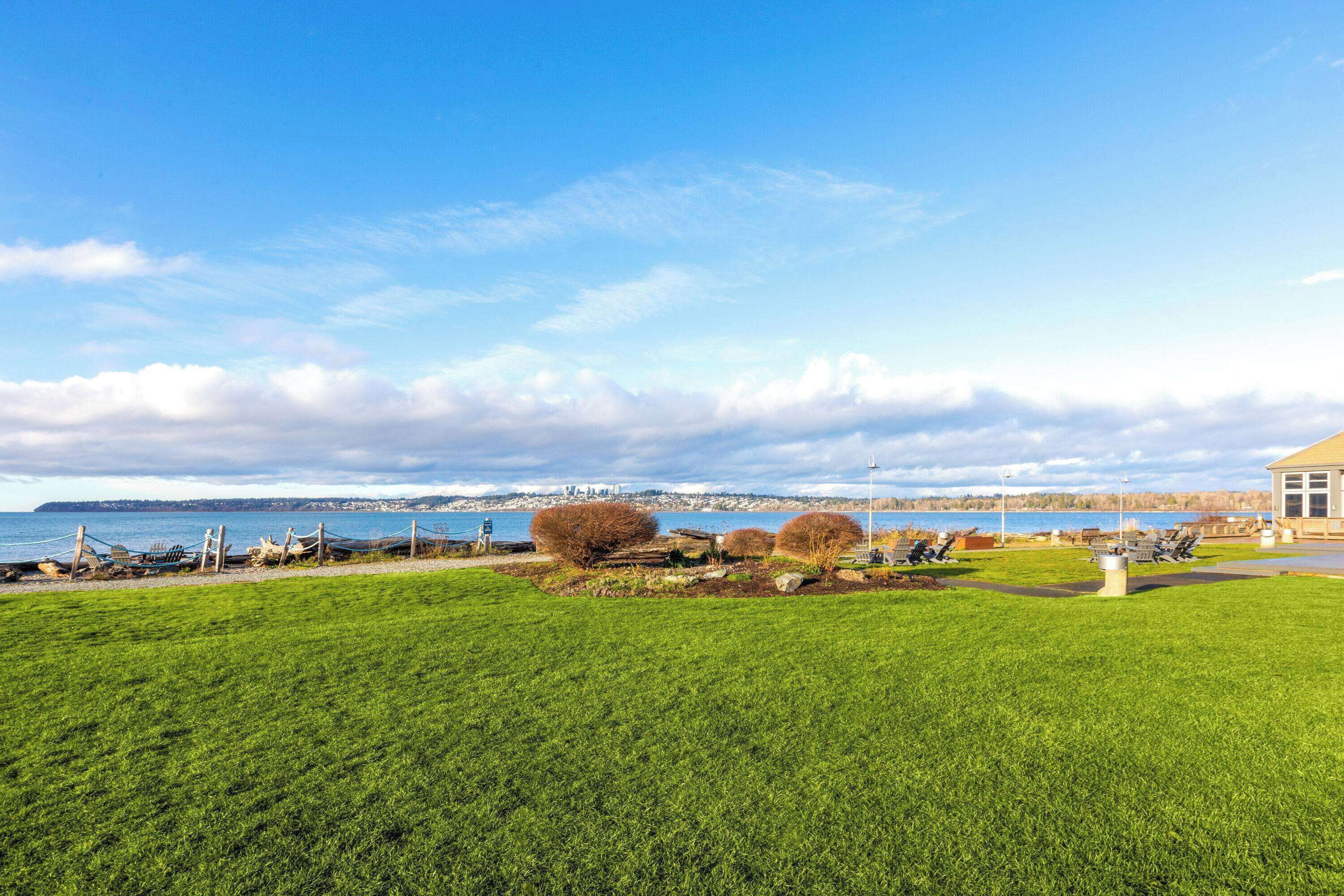 Une zone herbeuse offrant une vue sur la mer, avec un bâtiment en arrière-plan.