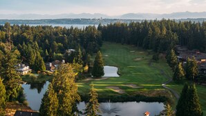 Golfkenttä, jonka yhteydessä on lampi, ja jota ympäröi tiheä metsä sekä asuinrakennuksia.