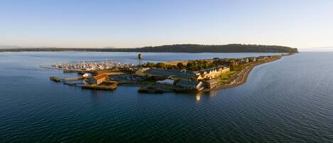 A coastal marina with docked boats, a water tower, and a row of buildings along the shore.