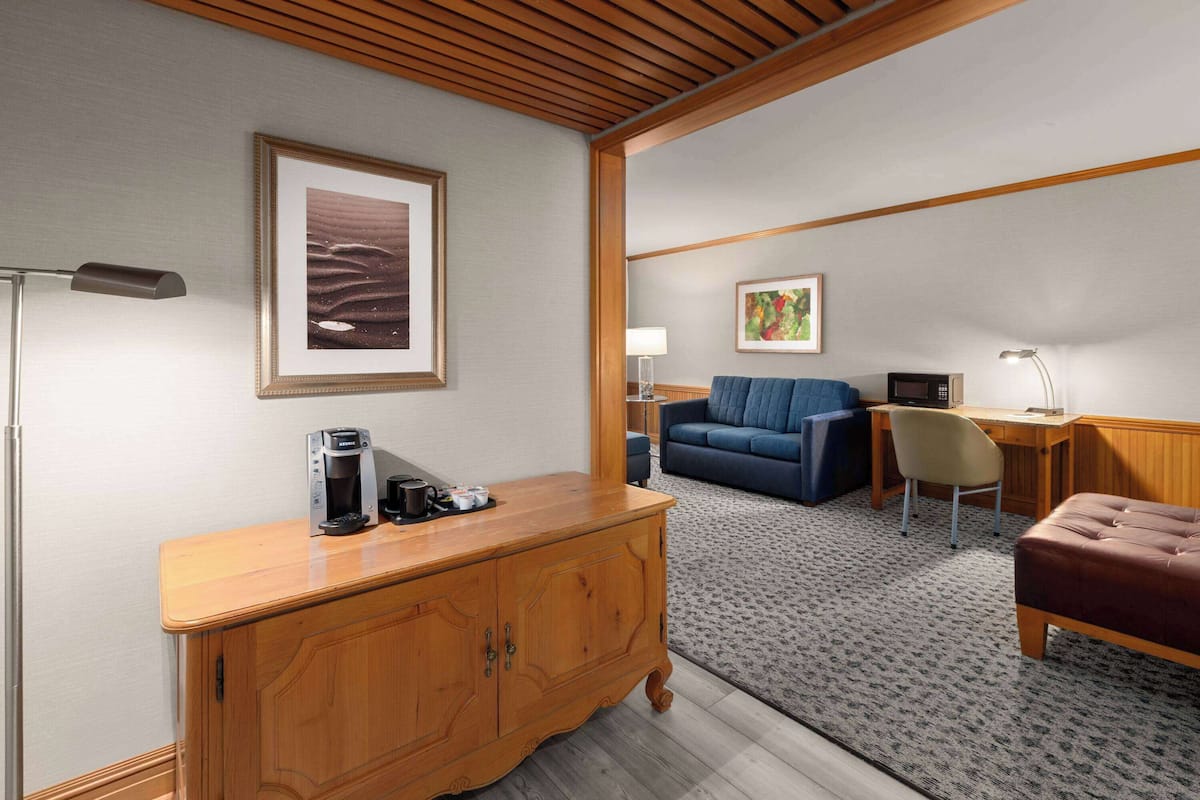 A hotel room with a wooden cabinet, a sofa, a desk, and a chair.