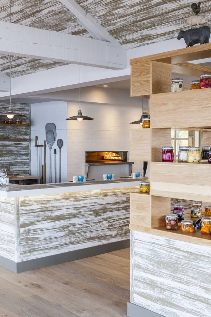 A rustic interior with a wooden reception desk, pendant lighting, and a display of jars.
