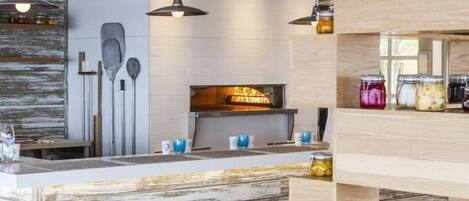 A rustic interior with a wooden reception desk, pendant lighting, and a display of jars.