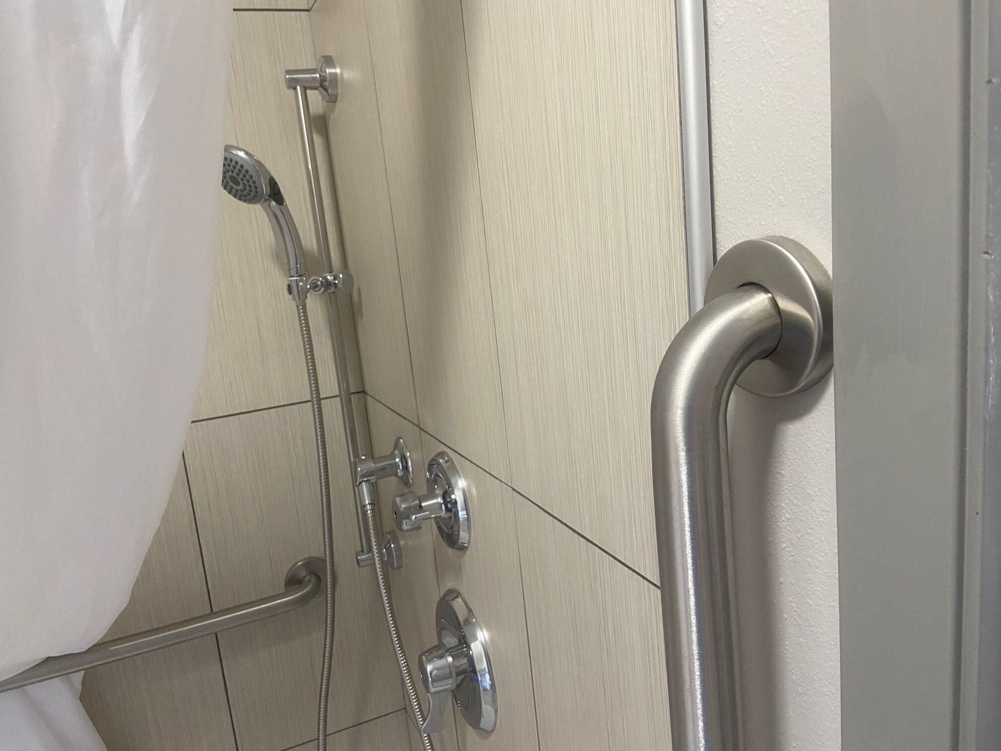 A shower with a handheld showerhead, a handheld shower nozzle, and a wall-mounted showerhead.