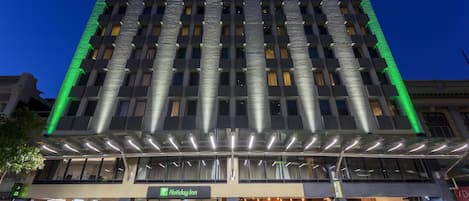 A multi-story hotel with a modern facade, a Holiday Inn sign, and a covered entrance area.
