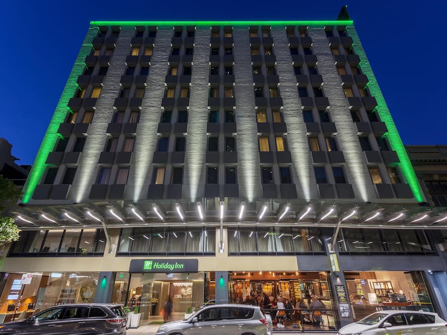 A multi-story hotel with a modern facade, a Holiday Inn sign, and a covered entrance area.