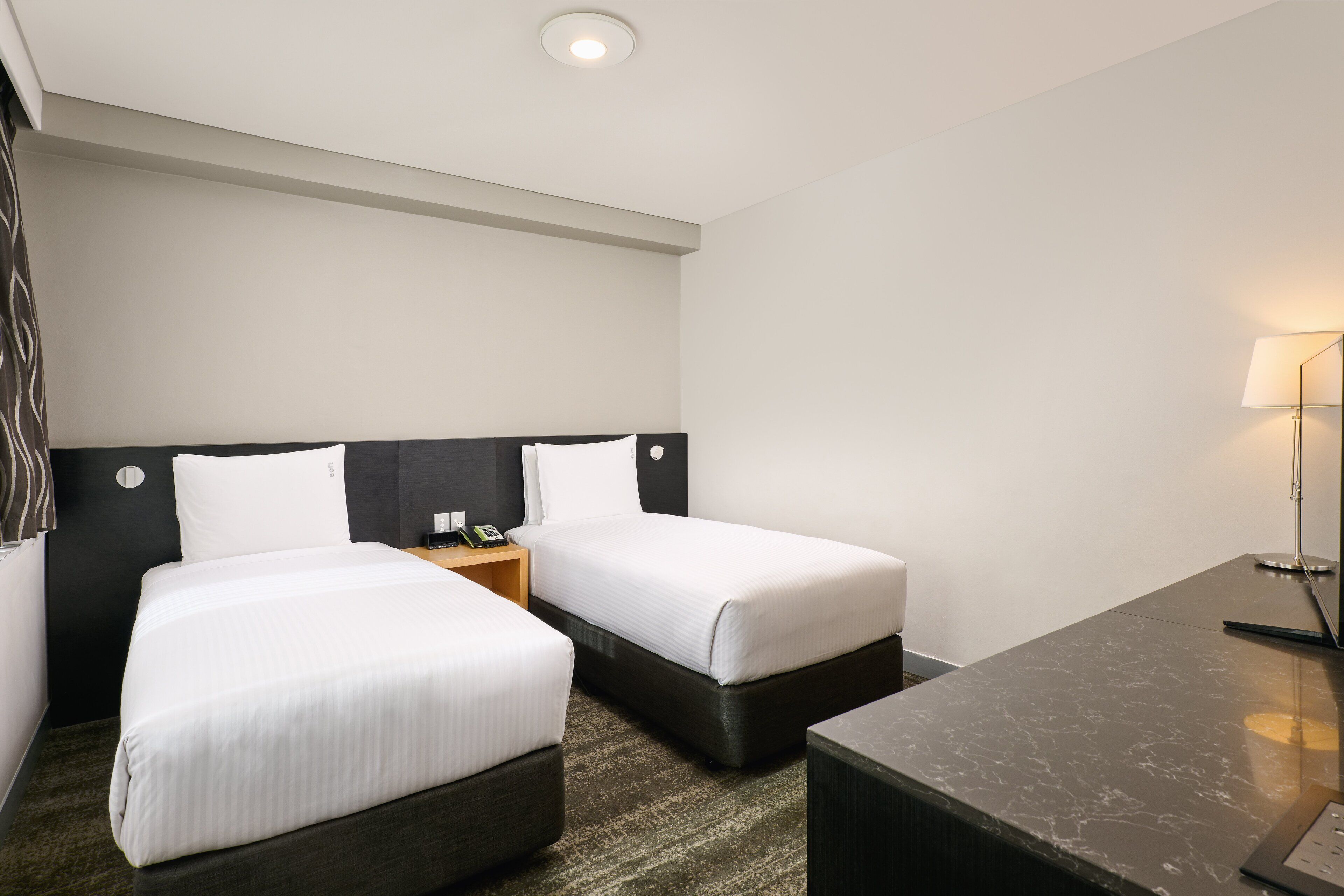 A hotel room with two beds, a desk, and a nightstand.