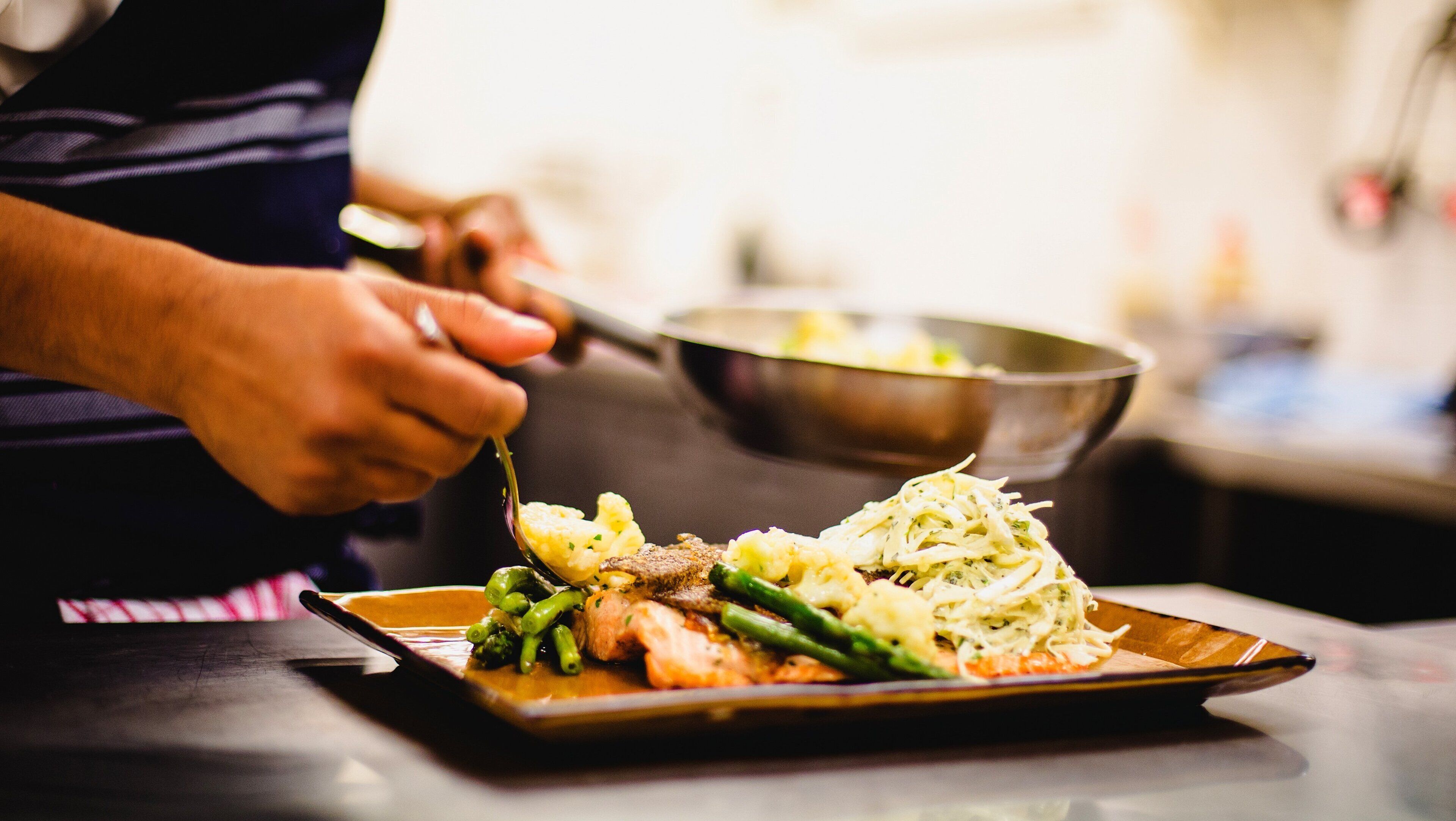 A person serving food onto a plate.