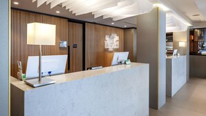 A modern reception desk with a marble counter, a computer, and a lamp. - Holiday Inn Perth City Centre by IHG (Perth)