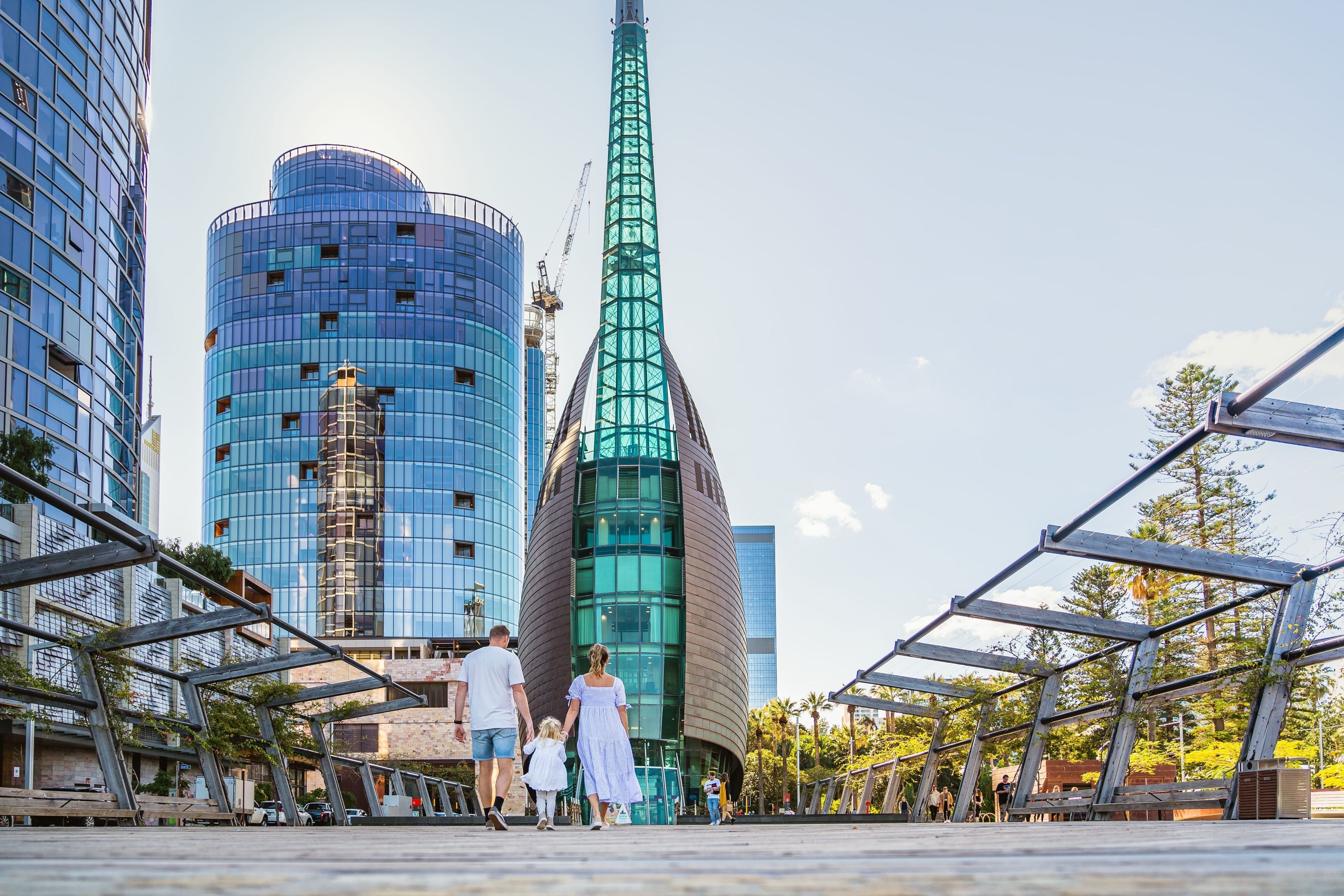 A modern urban setting with high-rise buildings, including a distinctive green tower.