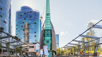 A modern urban setting with high-rise buildings, including a distinctive green tower.