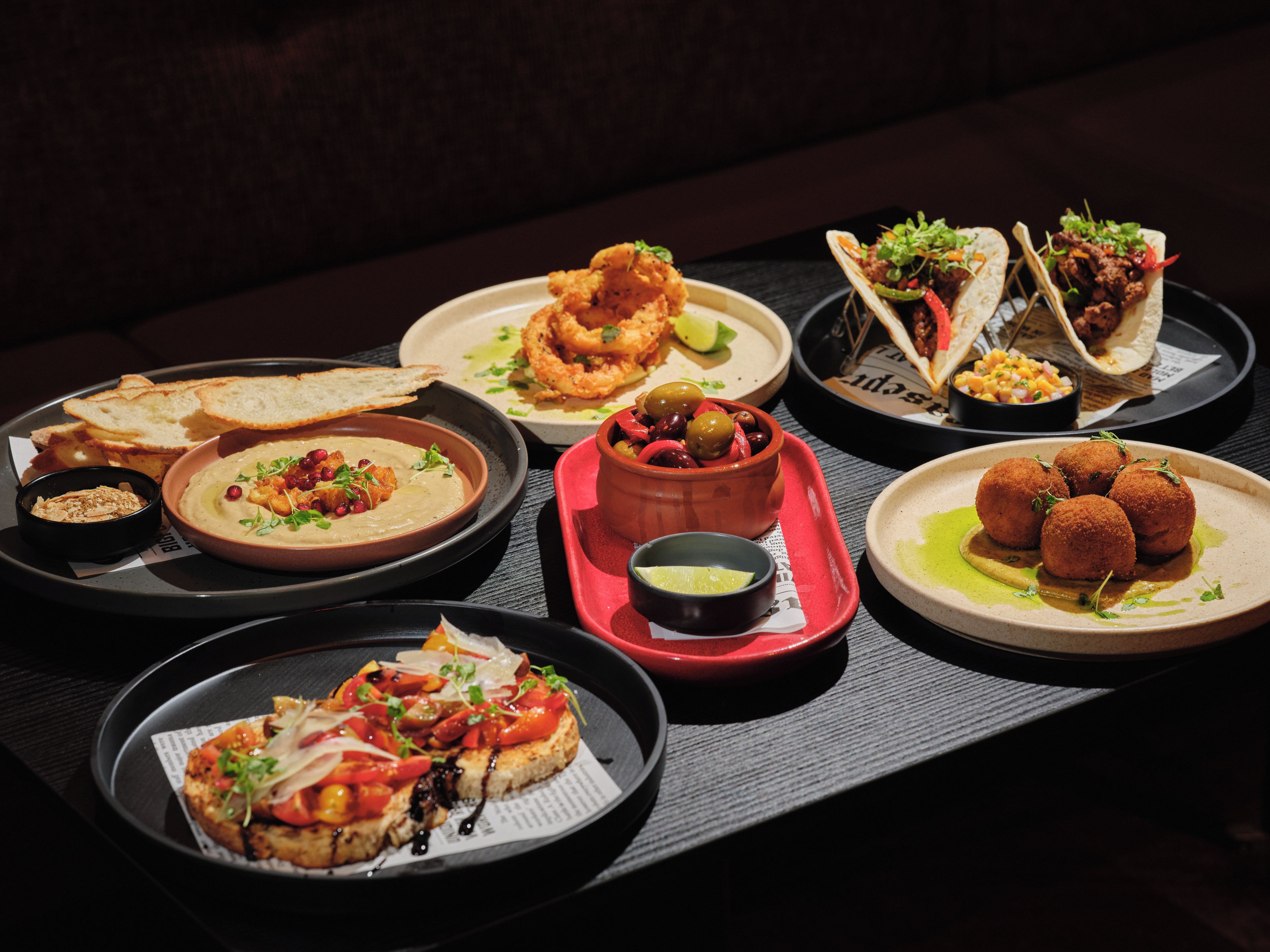 A variety of dishes on a tray, including bread, a bowl of soup, and what appears to be tacos.