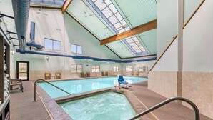 An indoor swimming pool with clear glass ceilings, multiple windows, and a seating area with chairs. - Best Western Plus Eagle/Vail Airport (Eagle)