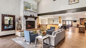 A spacious living area with a stone fireplace, comfortable seating, and a kitchen in the background. - Best Western Plus Eagle/Vail Airport (Eagle)
