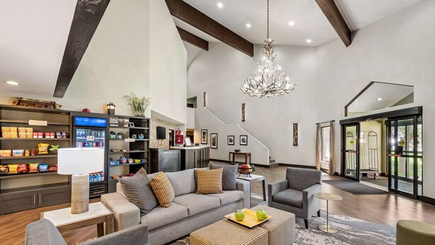 A spacious living area with a grey sofa, a coffee table with apples, and a modern chandelier. - Best Western Plus Eagle/Vail Airport (Eagle)