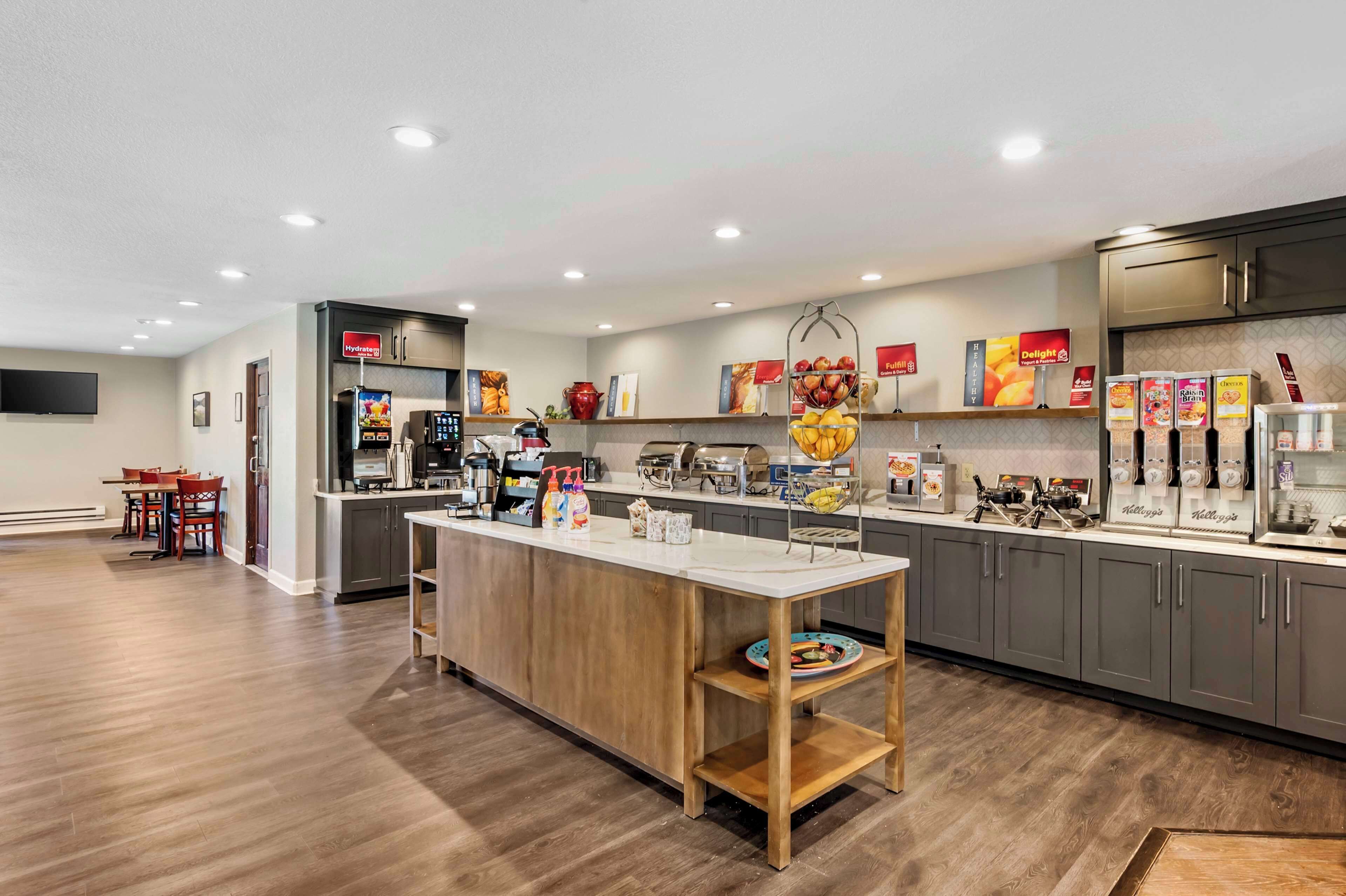 Una cocina moderna con una isla central, electrodomésticos integrados y una variedad de alimentos exhibidos en estantes.