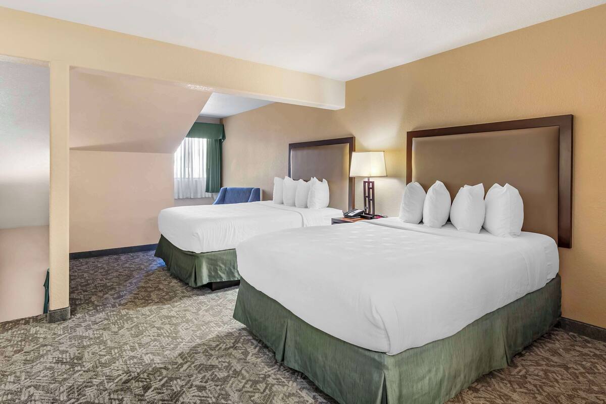 A hotel room with two beds, a sitting area, a lamp, and a telephone.