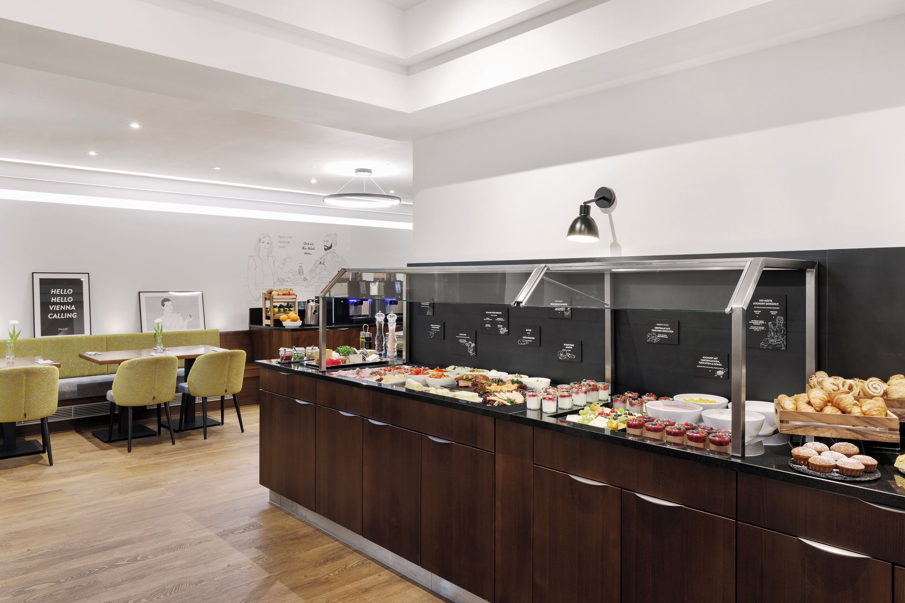 Een modern ontbijtbuffet met diverse keuzes, een zithoek met gele stoelen, en een schoon, minimalistisch design.