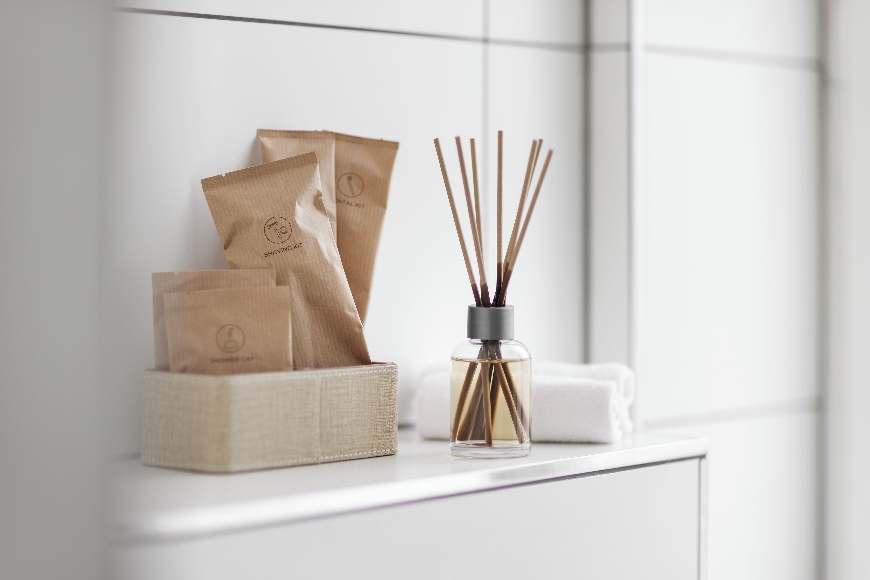 A bathroom counter with a shaving kit, a reed diffuser, and a towel.