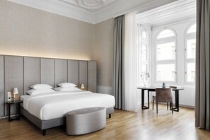 A modern hotel room with a large bed, bedside tables, a desk, and a chair.