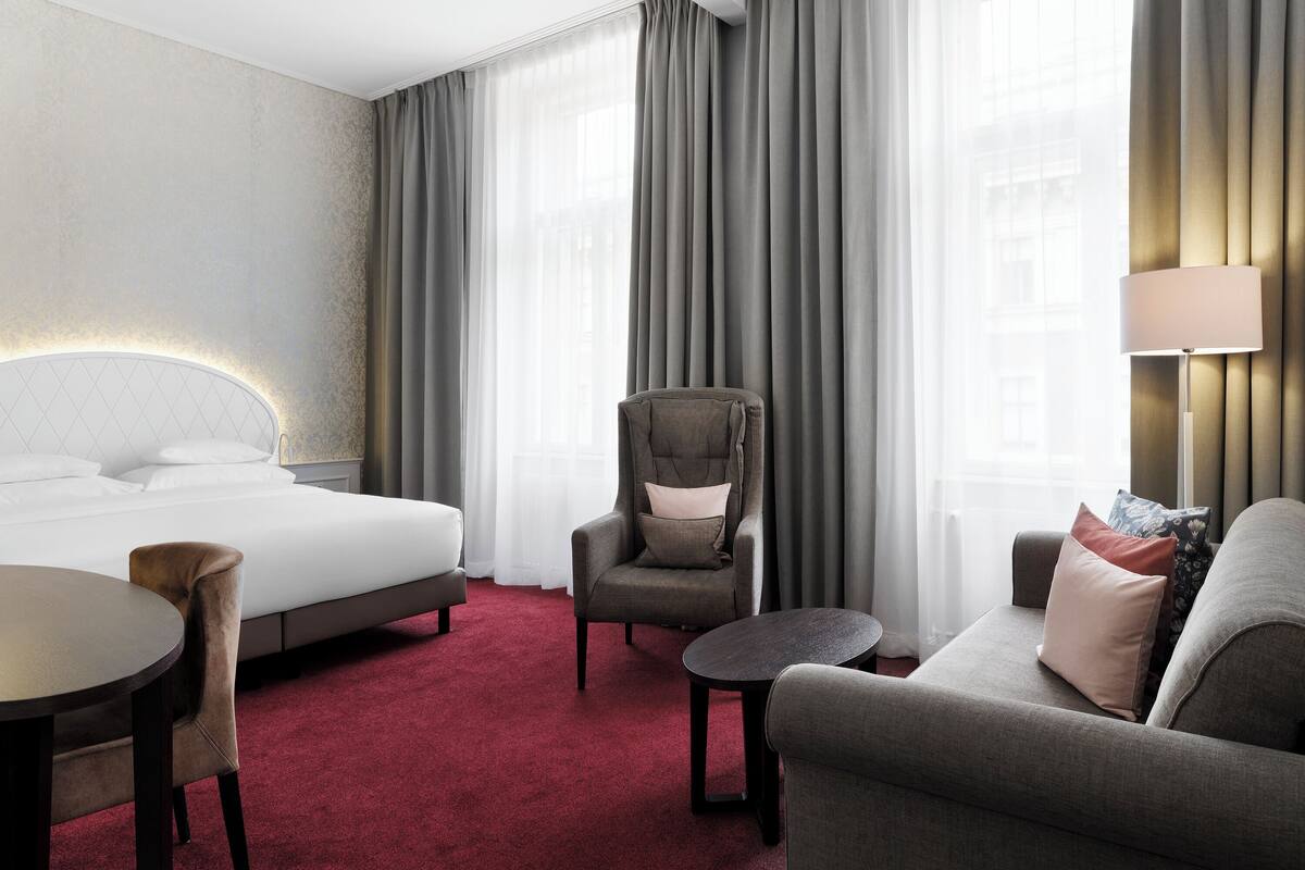 Een hotelkamer met een bed, een stoel, een bank en een kleine tafel.