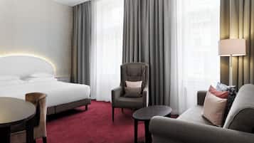 Et hotelværelse med en seng, en stol, en sofa og et lille bord.
