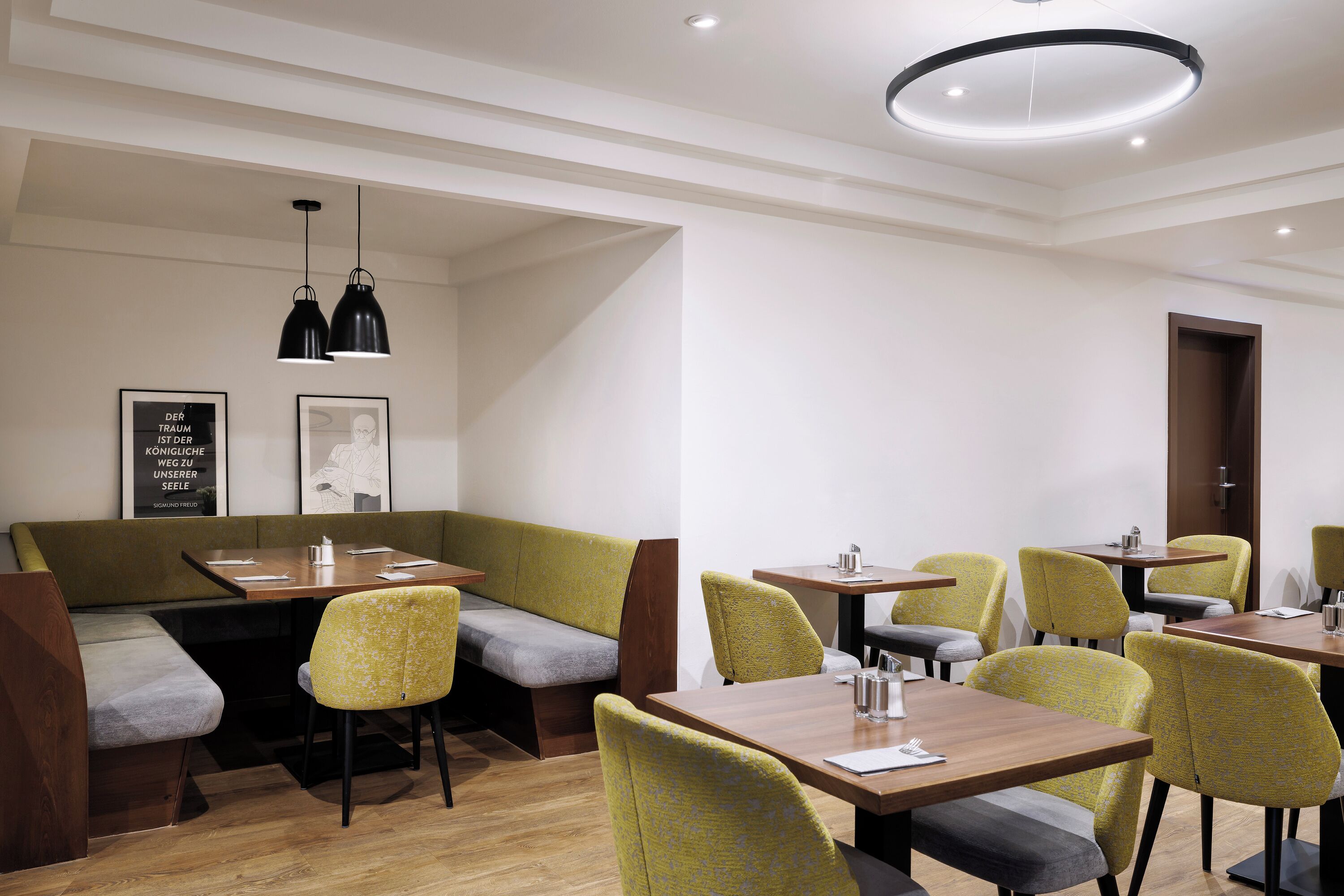 Un restaurante moderno con mesas de madera y asientos tapizados en tono verde.