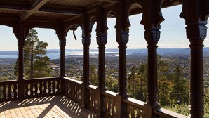A wooden balcony with ornate columns and a view of a town and lake. - Scandic Holmenkollen Park (Oslo)