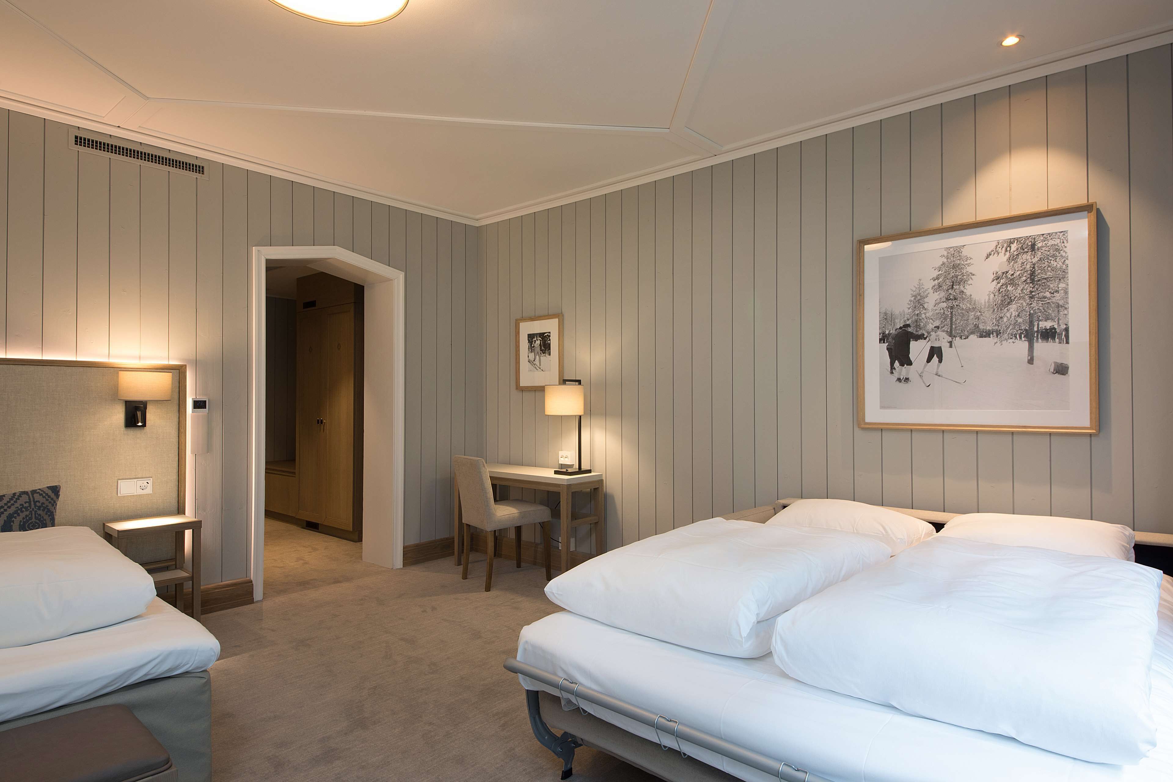 Une chambre d’hôtel avec deux lits, un bureau et une chaise.