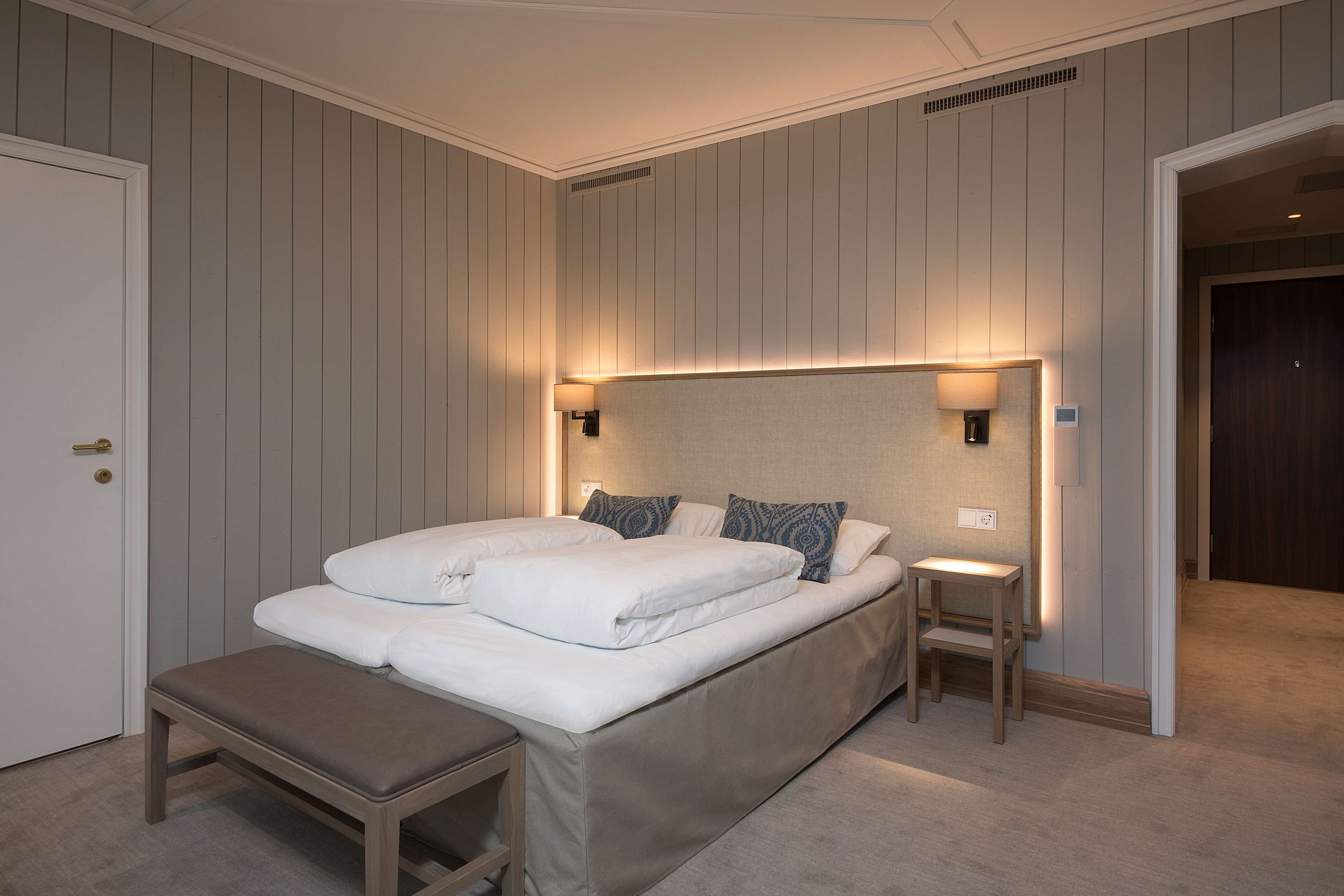A bedroom with a large bed, bedside tables, and a bench.