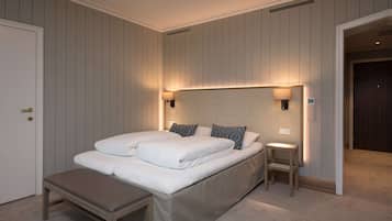 Un dormitorio con una cama grande, mesitas de noche y un banco.