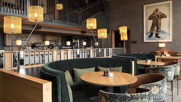 Un área de bar moderna con asientos, una escalera y un cuadro en la pared.