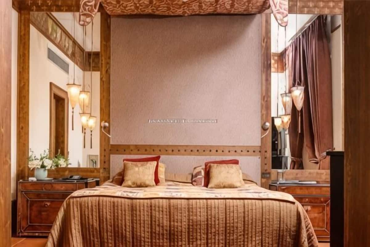 Ein Schlafzimmer mit einem großen Bett, einem Holzkopfstück, einem Spiegel und einer Kommode.