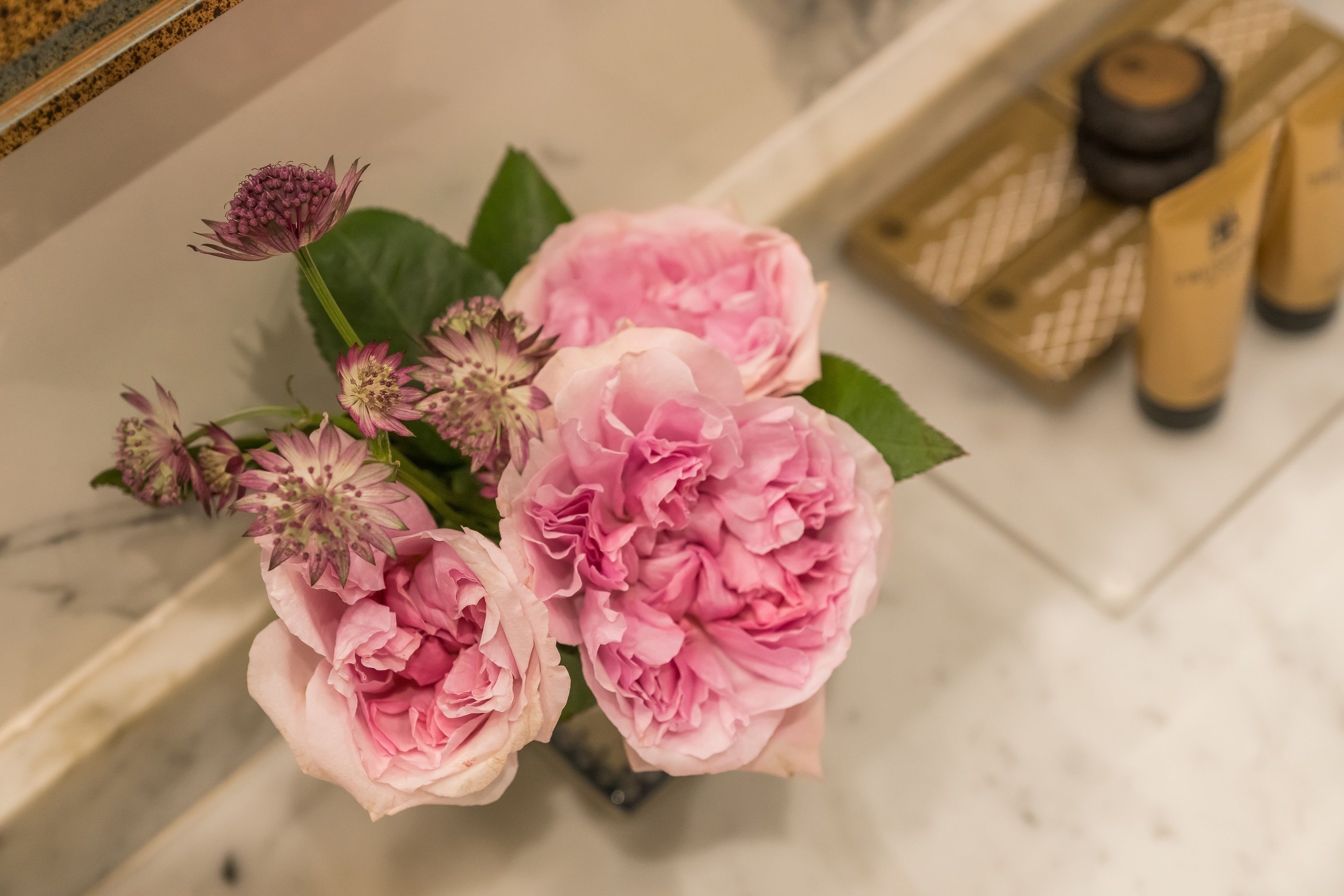 A bouquet of pink flowers in a vase on a marble surface.