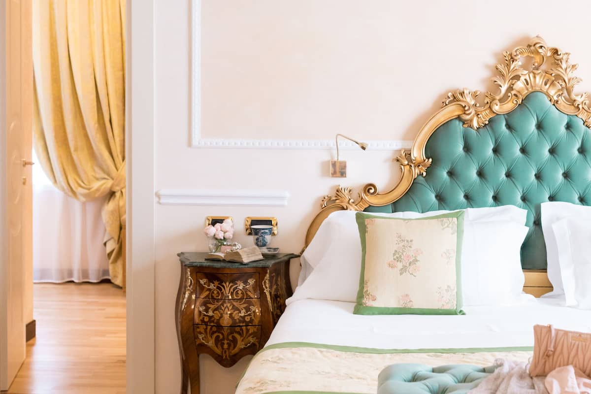 Ein Schlafzimmer mit einem großen Bett, einer Pendelleuchte, einem Nachttisch und einer Tür zu einem anderen Raum.