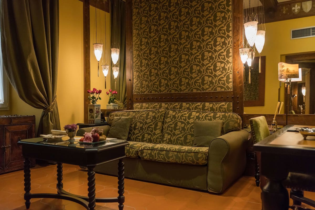Ein gemütliches Wohnzimmer mit einer gemusterten Couch, einem kleinen Tisch mit Blumen und einem Essbereich mit einer Lampe.
